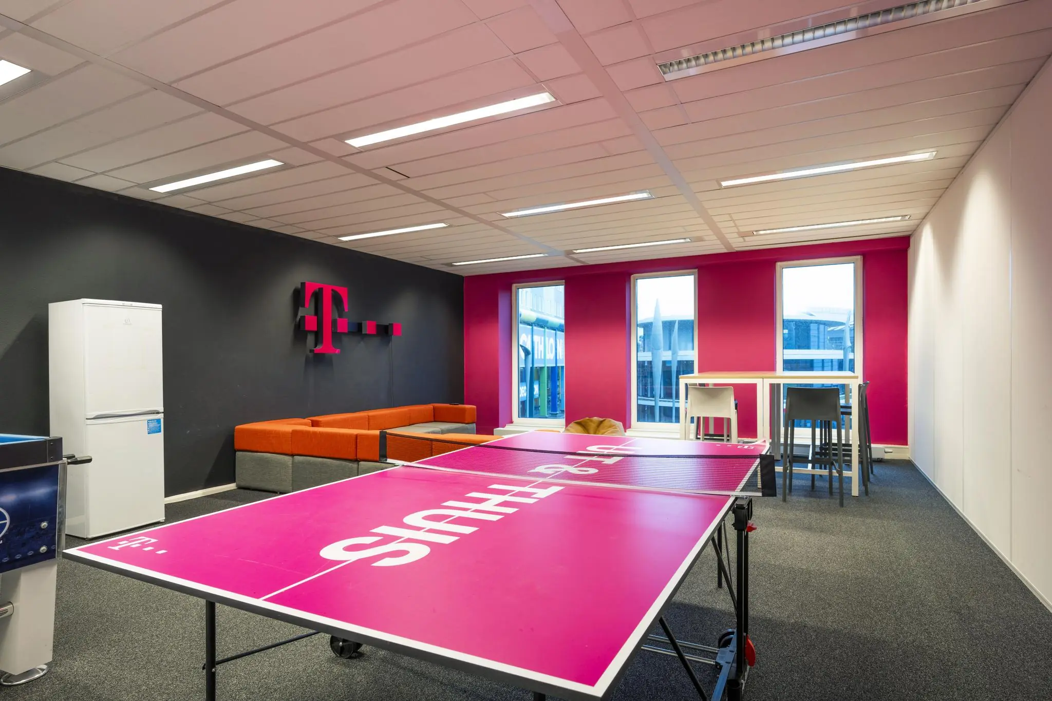 Moderne ontspanningsruimte op de Johan Cruijff Boulevard met T-Mobile branding, een tafeltennistafel en loungehoek.